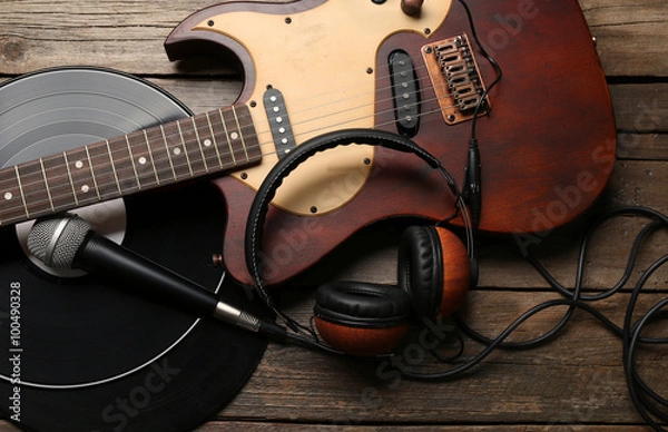 Fototapeta Electric guitar and headphones with microphone and vinyl on wooden background