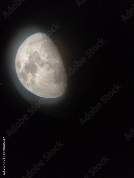 Fototapeta Luna creciente, vista parcial, en luz con halo alrededor se aprecian los mares y cráteres. Foto tomada a través de telescopio