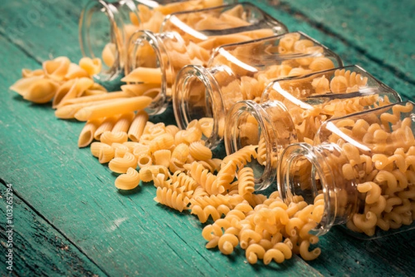 Fototapeta Various mix of pasta on wooden rustic background. Diet and food