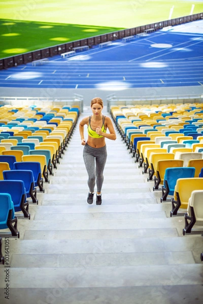 Fototapeta Young sportswoman is at large modern stadium