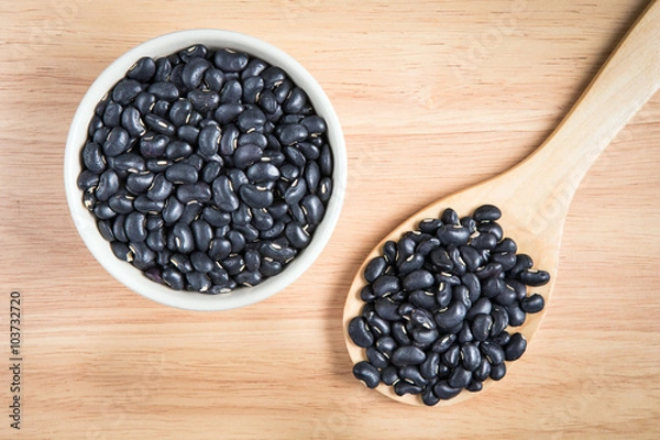 Fototapeta bowl of black bean and a scoop of black bean on the wood backgro