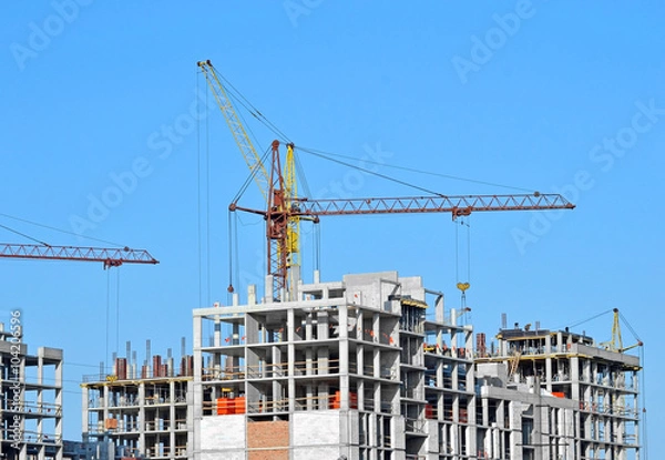 Fototapeta Crane and building construction site against blue sky