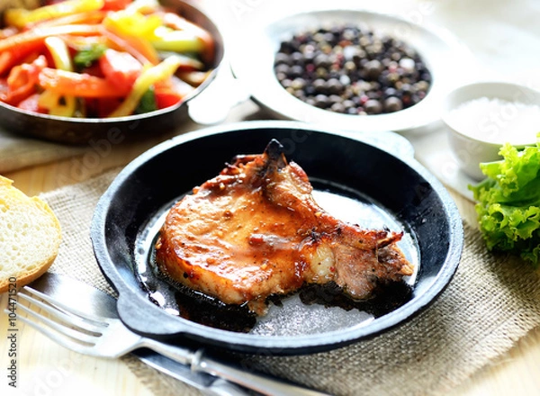 Fototapeta pork steak in a frying pan, fried vegetables