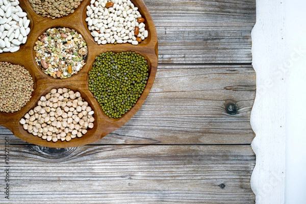 Fototapeta Wooden bowl of various legumes on wooden background copy space