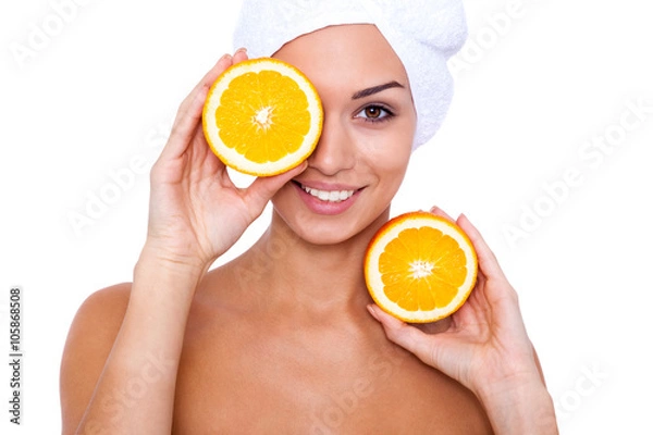 Fototapeta A young girl takes spa treatments with oranges in hand. White background.