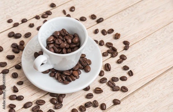 Fototapeta Cup of coffee beans with a spoon and saucer on a white background with the outline of more coffee beans