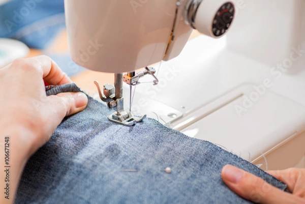 Fototapeta young woman sews on the sewing machine denim