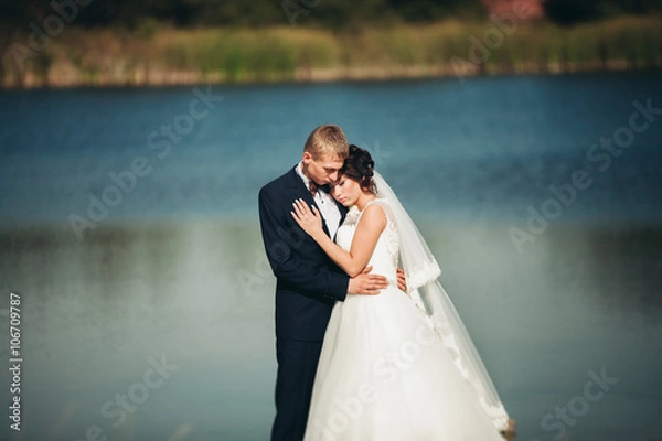 Fototapeta Love and passion - kiss of married young wedding couple near lake