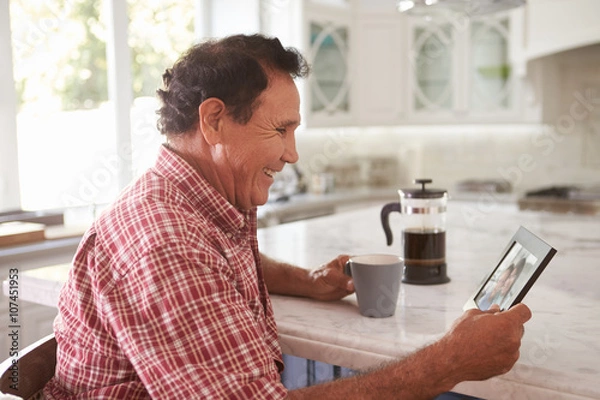 Fototapeta Senior Hispanic Man At Home Looking At Old Photograph