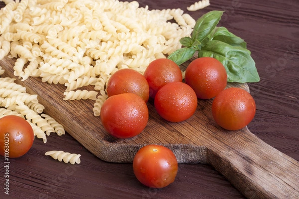 Fototapeta Dried pasta, tomatoes, basil on wooden background