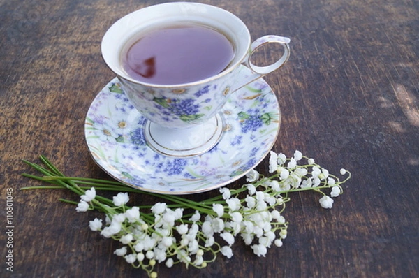 Fototapeta Tea cup, lily of the valley, on wooden background