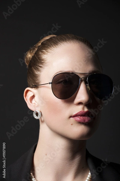 Fototapeta Portrait of Beautiful young woman in sunglasses on black backgro