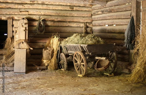 Fototapeta Wooden cart with hay in old barn.