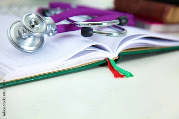 Obraz Stethoscope lying on a table on an open book