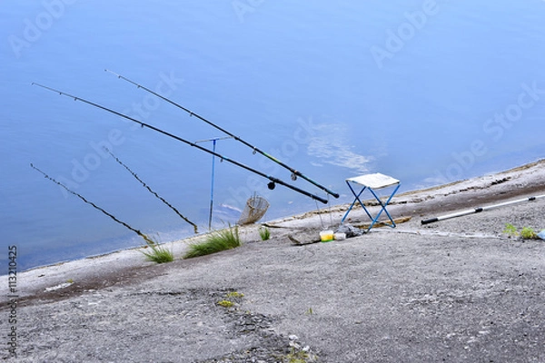 Fototapeta Chair with fishing poles and fishing equipment at the lake