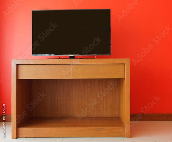 Obraz Flatpanel tv on wooden cabinet against orange wall