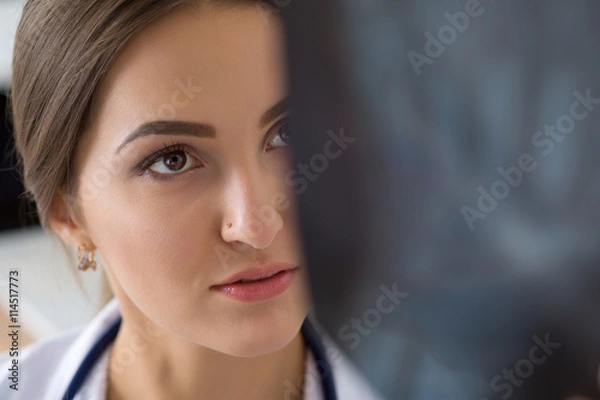 Fototapeta Young female medical doctor or intern looking at lungs x-ray ima