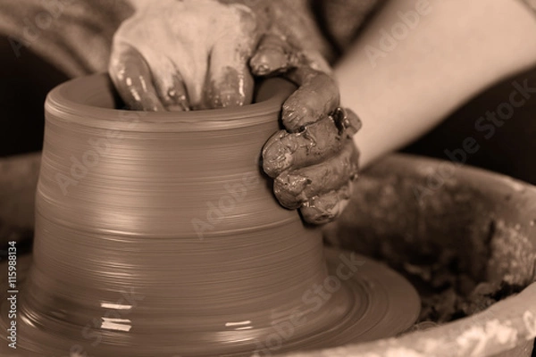 Fototapeta Potter shaping clay on the pottery wheel