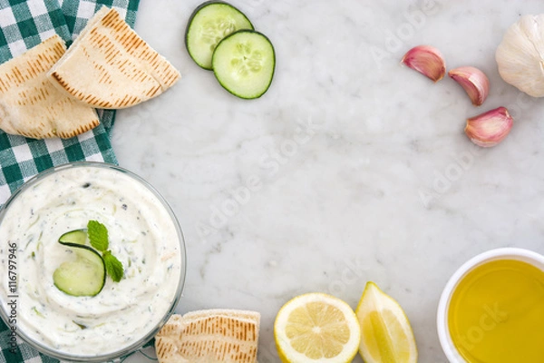 Fototapeta Tzatziki in bowl and ingredients on white marble
