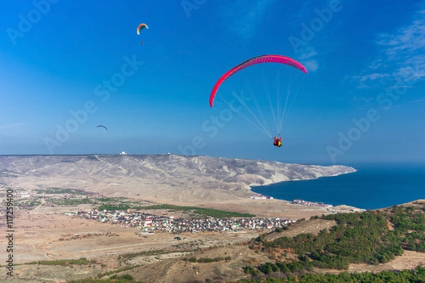 Fototapeta paragliders in flight over the sea coast