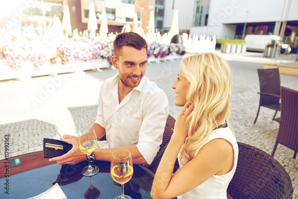 Fototapeta happy couple with wallet paying bill at restaurant