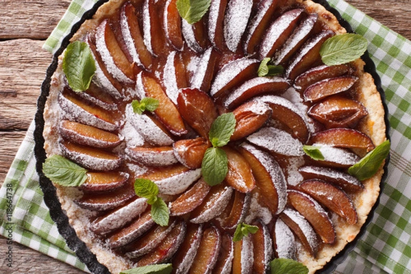 Fototapeta Plum cake with mint and powdered sugar in baking dish close up. Horizontal top view
