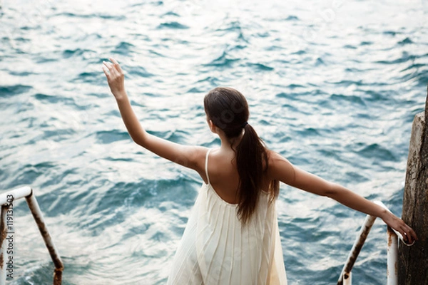 Fototapeta Young beautiful ballerina dancing and posing outside, sea background.