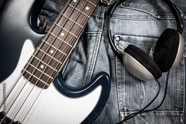 Fototapeta blue electric bass guitar and headphone on denim jeans for music background