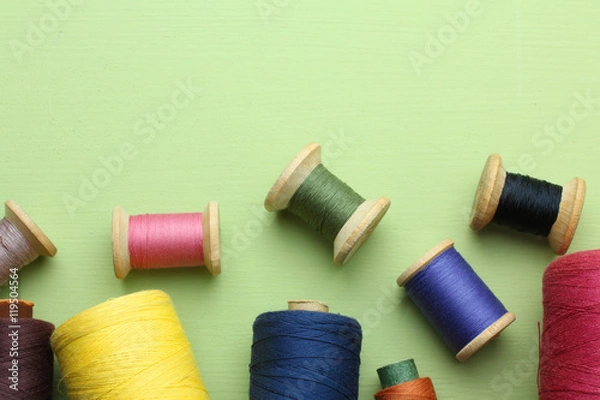 Fototapeta Spool of thread on wooden green  background