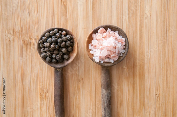 Fototapeta Salt and pepper seasonings of pepper corns and rock salt on wood