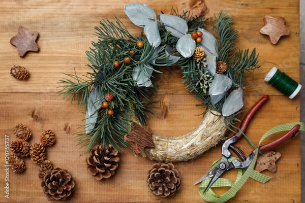 Fototapeta Top down view of florist's worktable. Making of Christmas wreath. Copy space - perfect for a festive card.