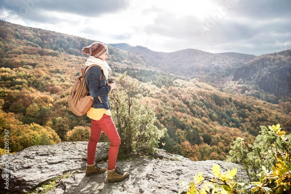 Fototapeta Beautiful woman with backpack against colorful sunny autumn fore