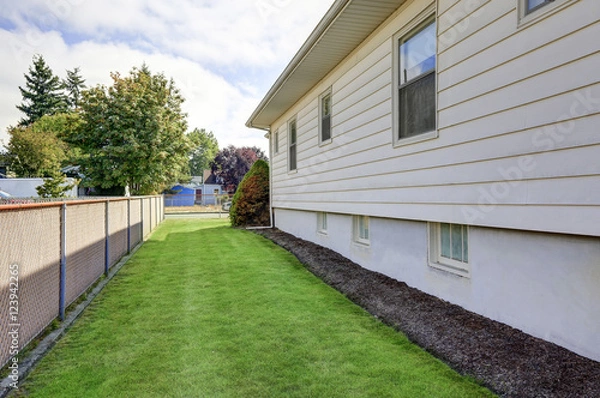 Fototapeta House exterior. View of side wall and green grass.