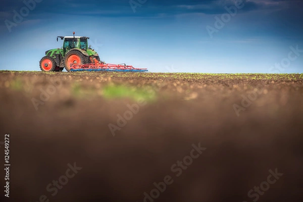 Fototapeta Farmer in tractor preparing land with seedbed cultivator