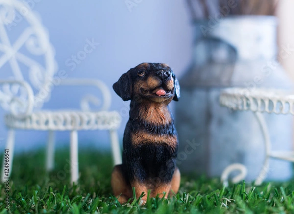 Fototapeta Ceramic dog sit on the grass with blur background
