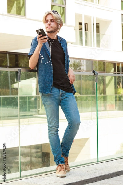 Fototapeta Hipster man standing with earphones talking on phone