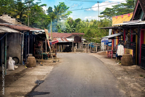 Fototapeta street in a village in lombok with forest in the background