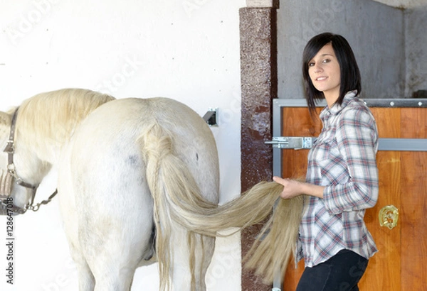 Fototapeta Beautiful young girl and white horse in the stable