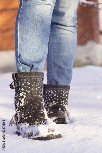 Fototapeta Woman's legs with blue jeans and black shoes in a snow