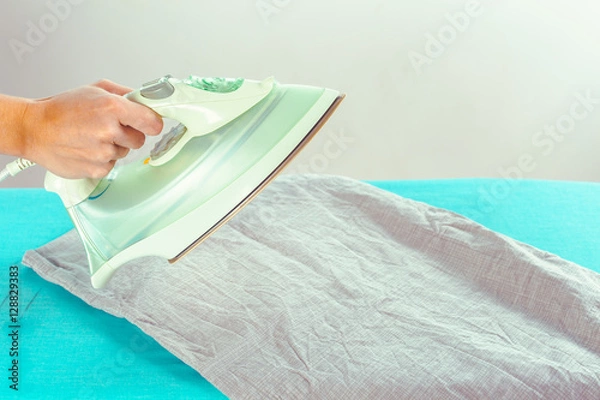 Fototapeta Closeup of woman ironing clothes on ironing board