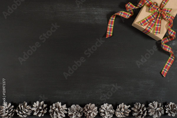 Fototapeta Gift box with cones on the black board.