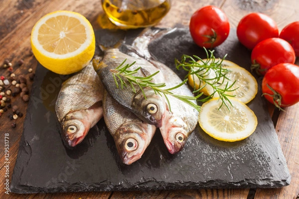 Fototapeta fish with a lemon and tomatoes on a table, selective focus