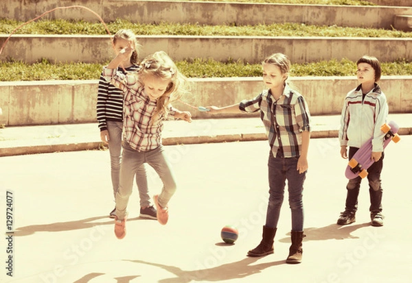 Fototapeta Smiling girl jumping while jump rope game