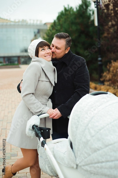 Fototapeta Family walk in the autumn park with a pram. Mom, dad and baby ou