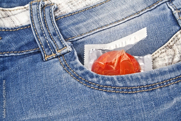 Fototapeta Red condom in blue jeans pocket