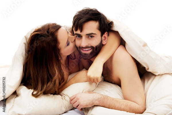 Fototapeta Beautiful couple under the cover in their bed.