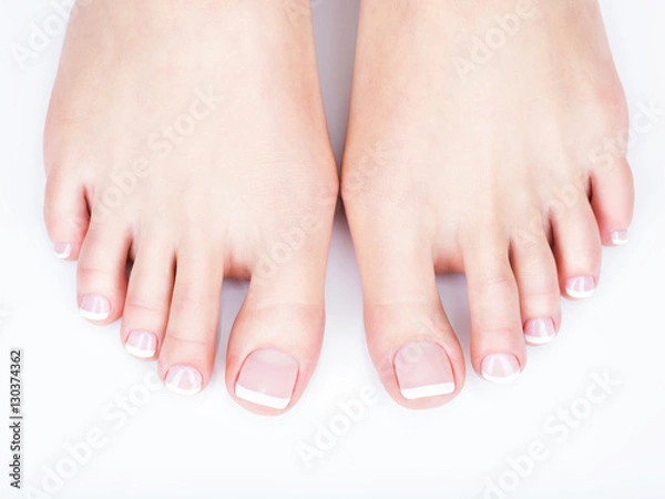 Obraz female feet with white french pedicure on nails. at spa salon