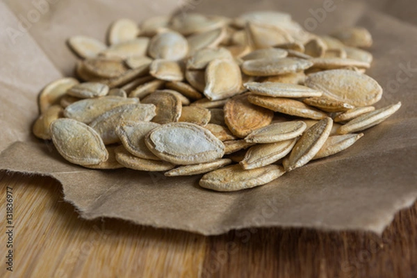 Fototapeta Grilled Pumpkin seeds with sea salt and spices on the wooden background