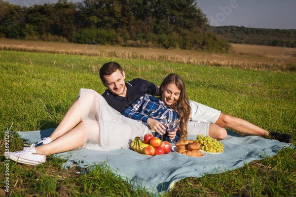 Fototapeta young happy couple at picnic on the lawn