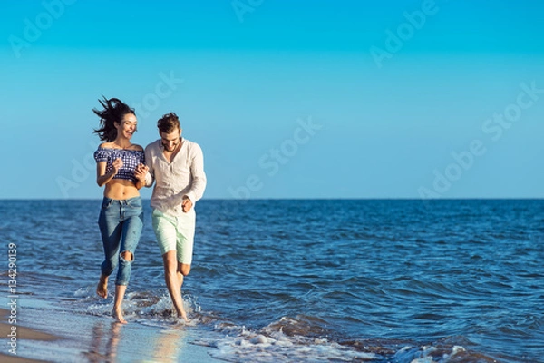 Fototapeta happy couple running on the beach